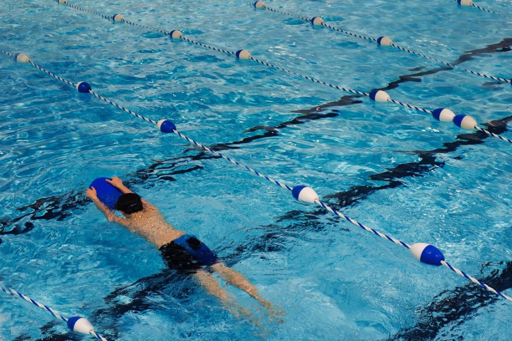 A man swimming at the miller swimming pool with a black and blue swim trunk A man swimming at the miller swimming pool with a black and blue swim trunk