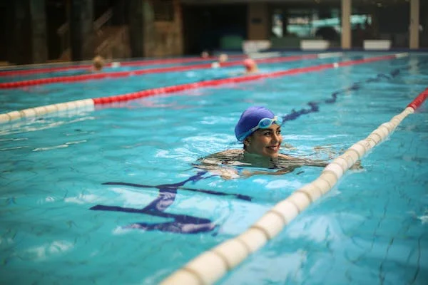 a motivated female swimmer smiling in the middle of a swimming pool
