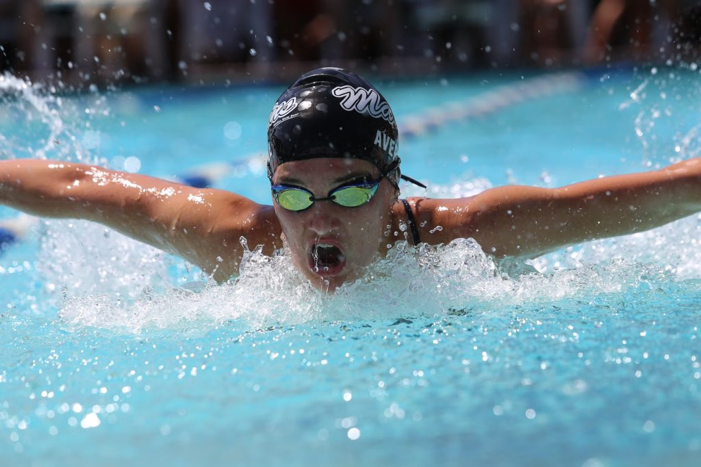 a male swimmer swimming with black cap and swim goggles