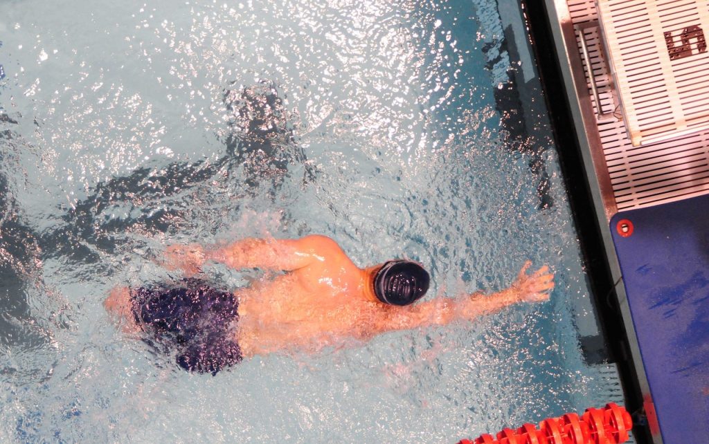 male swimmer keeping a streamlined body position to do the open turn