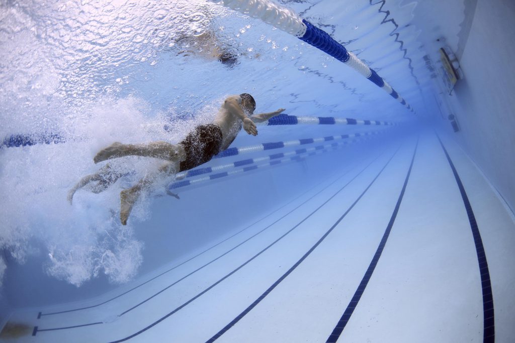 male swimmer doing the freestyle swimming to build his lower body muscles