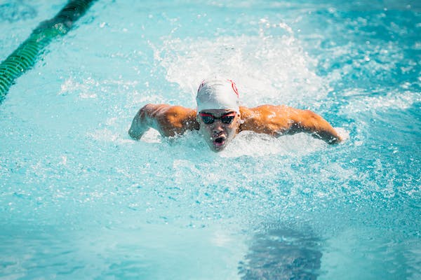 male swimmer swimming with a white swim cap