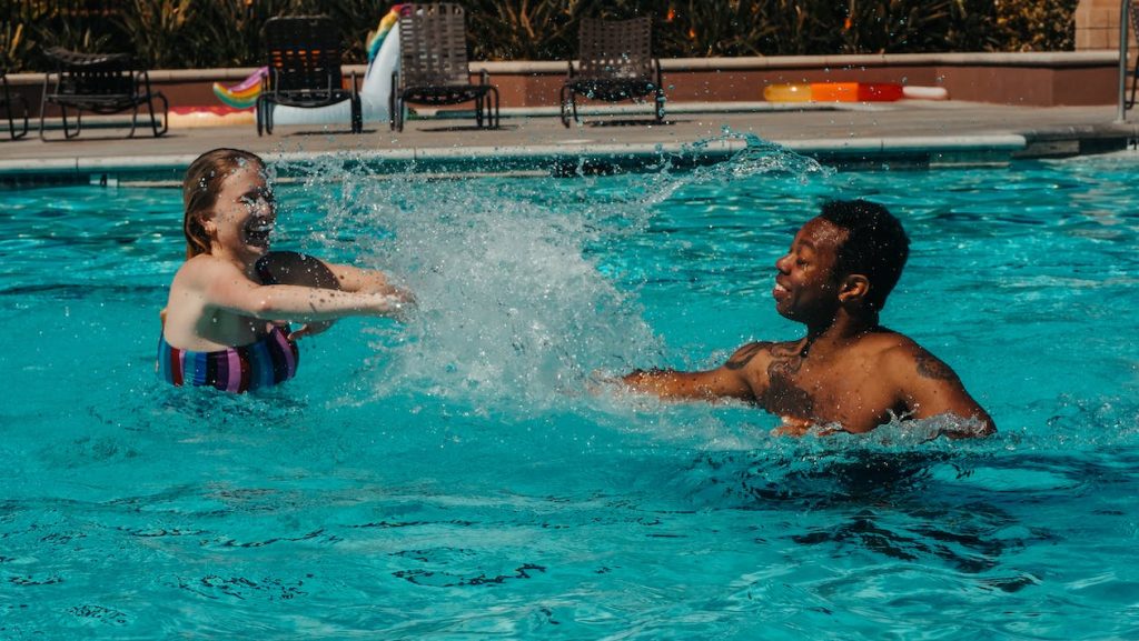 female swimmer swimming in the pool with her swim instructor
